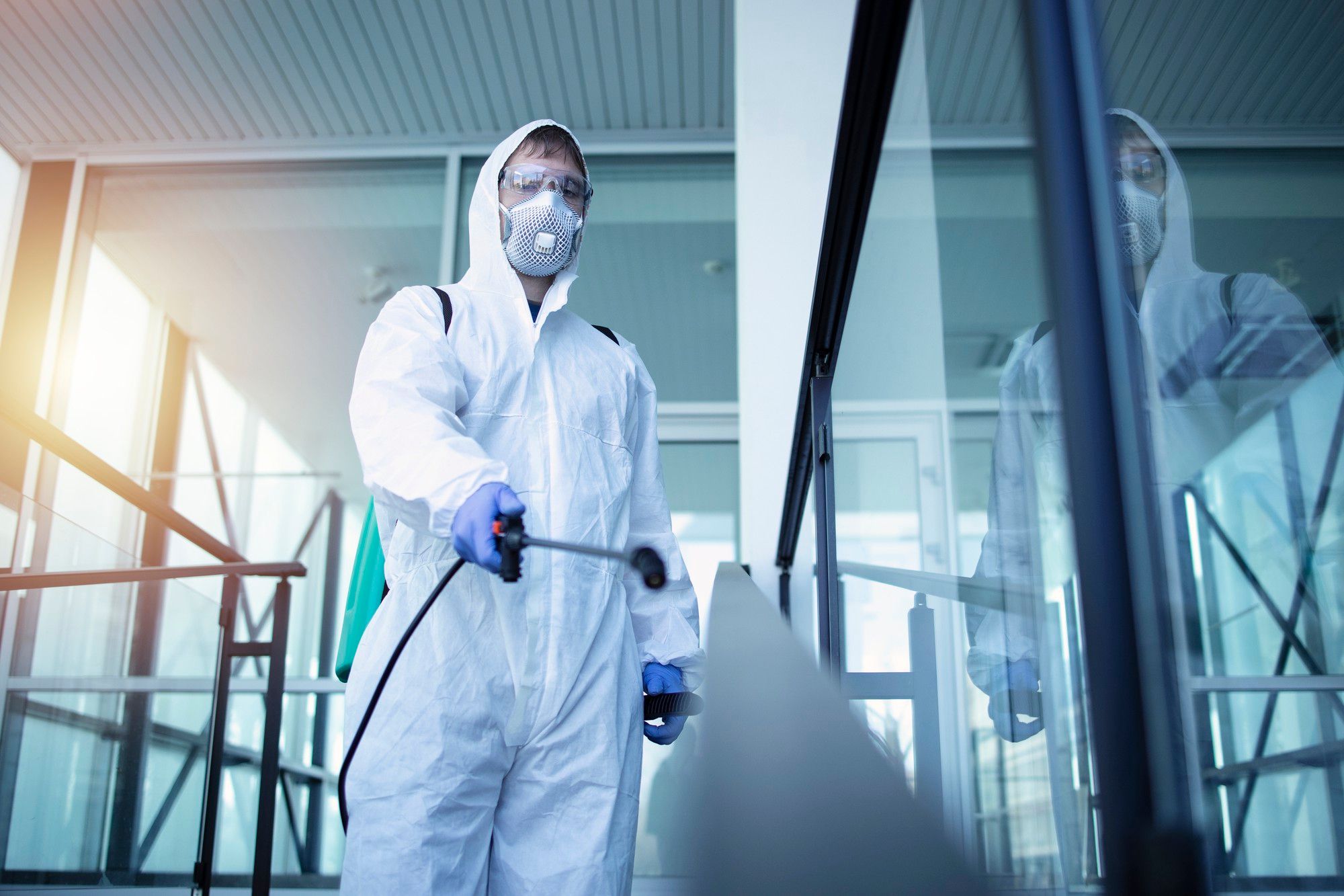 exterminator in uniform holding toxic spray and showing thumb up